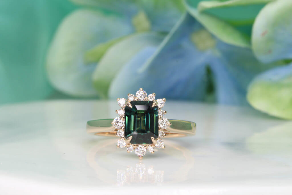 Teal Sapphire Engagement ring customised with alternate sizes diamond, gives a star burst look to the overall design. Crafted in 750 18k Rose gold bands, regal and radiant, this exquisite engagement ring was crafted to perfection | Customised Engagement Ring Teal Sapphire Singapore