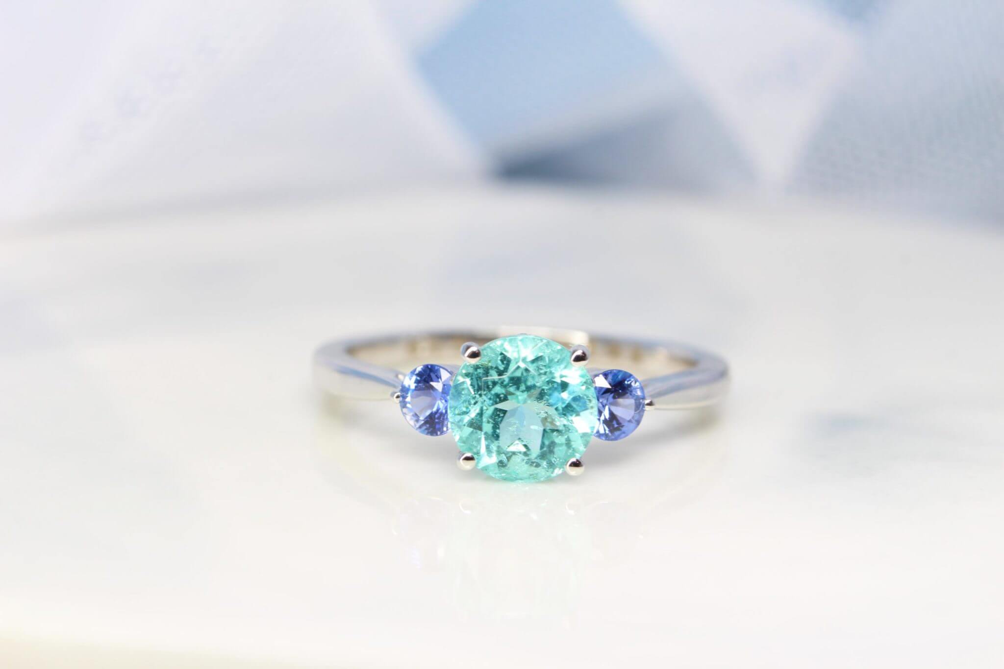 Engagement Ring with Paraiba Tourmaline customised with round blue tanzanite gemstone in 750 white gold band, unique customised engagement ring without diamond but customised with coloured gemstone for one of a kind design Local Singapore Jeweller in customised engagement ring with paraiba tourmaline gemstone.